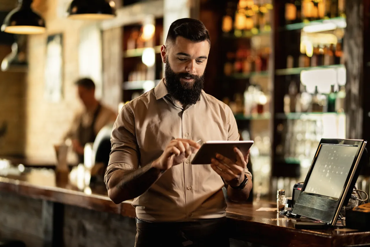Ein Barista bedient hinter der Bar das Tablet.