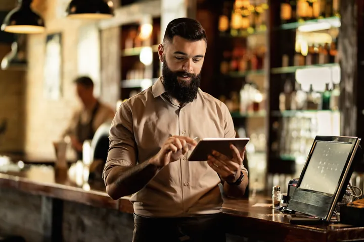 Ein Barista bedient hinter der Bar das Tablet.